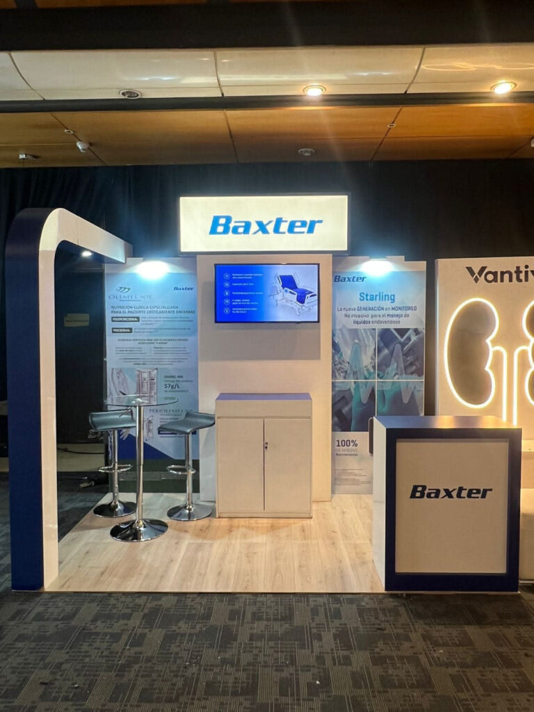Stand de exposición de Baxter con letreros luminosos, pantallas de visualización, carteles informativos, dos taburetes de bar y un mostrador de recepción sobre un suelo con motivos de madera.
