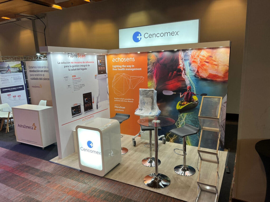 Stand de exposición para Cencomex con expositores de marca, material promocional, taburetes altos, una mesa y un cartel retroiluminado, con la imagen de un kayak de fondo.